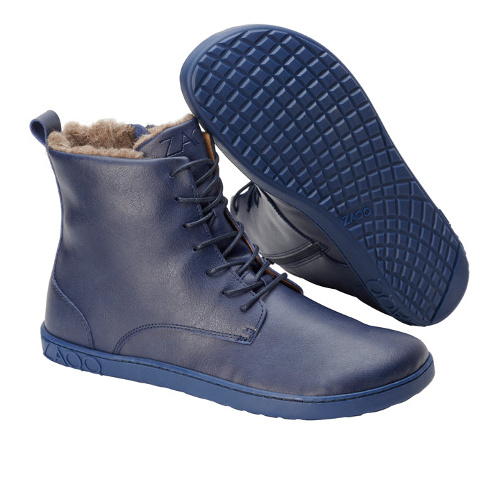 Präsentiert wird der QUINTIC Winter Navy von ZAQQ mit einem Paar marineblauer Schnürstiefeletten. Ein Stiefel steht aufrecht und hebt das Kunstfellfutter hervor, während der andere so positioniert ist, dass die strukturierte Sohle sichtbar ist. Diese Stiefel sind aus hochwertigen veganen Materialien gefertigt und weisen ein elegantes Design mit einem glatten, lederähnlichen Finish auf.