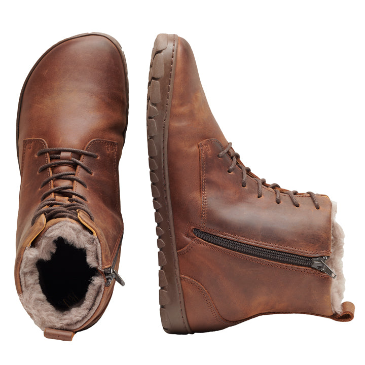 Die QUINTIC Winter Antique Brown Stiefel von ZAQQ haben einen seitlichen Reißverschluss und eine Schnürung vorne. Der linke Stiefel steht aufrecht und hebt das kuschelige Lammfell-Futter hervor, während der rechte Stiefel auf der Seite liegt und sowohl die Sohle als auch den Reißverschluss zeigt. Diese Stiefel bieten ein robustes, lässiges Design, ideal für abenteuerliche Tage.