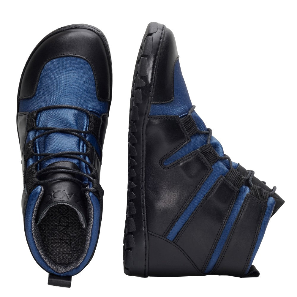 Die DAQOTA Waterproof Ocean High-Top-Sneaker von ZAQQ bestechen durch ihr schlichtes Design. Diese Barfußschuhe bestechen durch eine auffällige Kombination aus schwarzem Leder und blauem Stoff, akzentuiert durch schwarze Schnürsenkel und markante Riemendetails. Für eine umfassende Ansicht wird ein Schuh von oben präsentiert, während der andere von der Seite gezeigt wird.