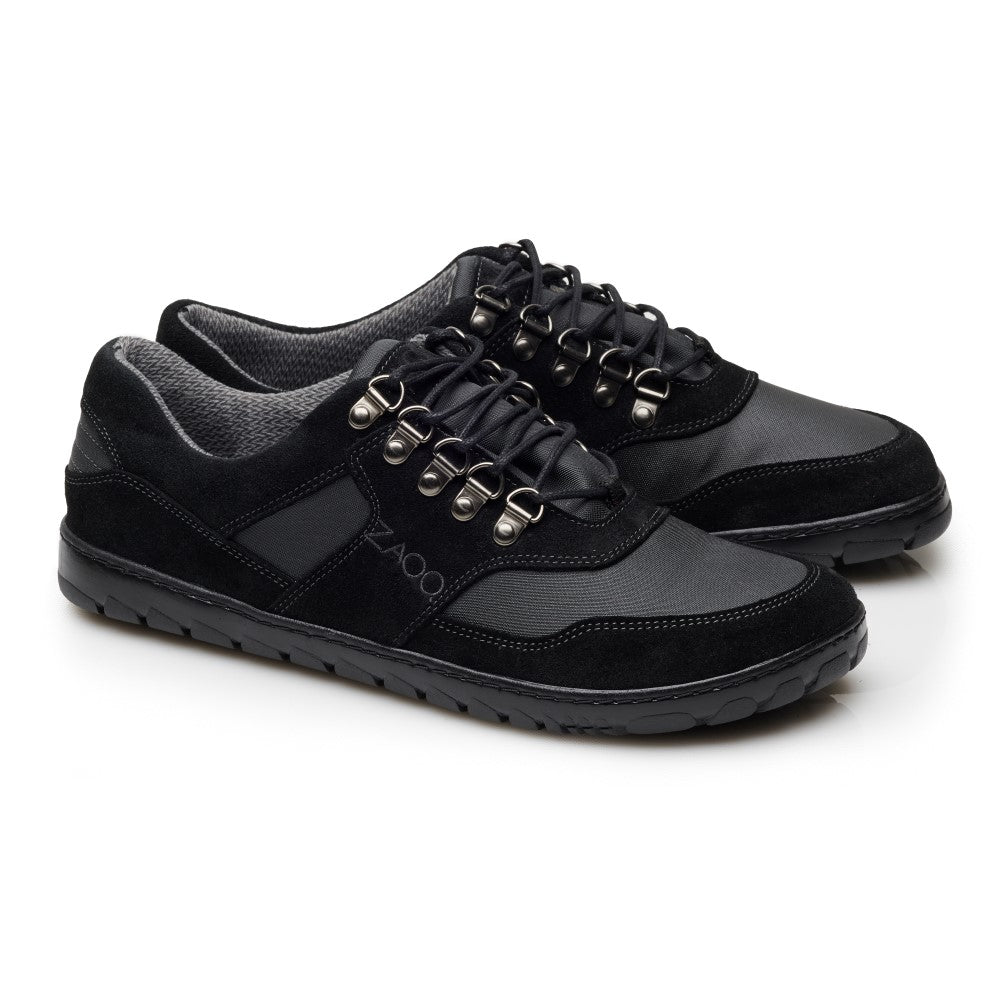 Die HIQE Low Black Waterproof-Schuhe von ZAQQ haben schwarze Schnürsenkel, silberne Ösen und eine Outdoor-Sohle. Ihre strukturierte Sohle passt perfekt zu einer Mischung aus glatten und wildlederähnlichen Materialien im oberen Teil. Der Markenname ZAQQ ist an der Seite deutlich sichtbar.