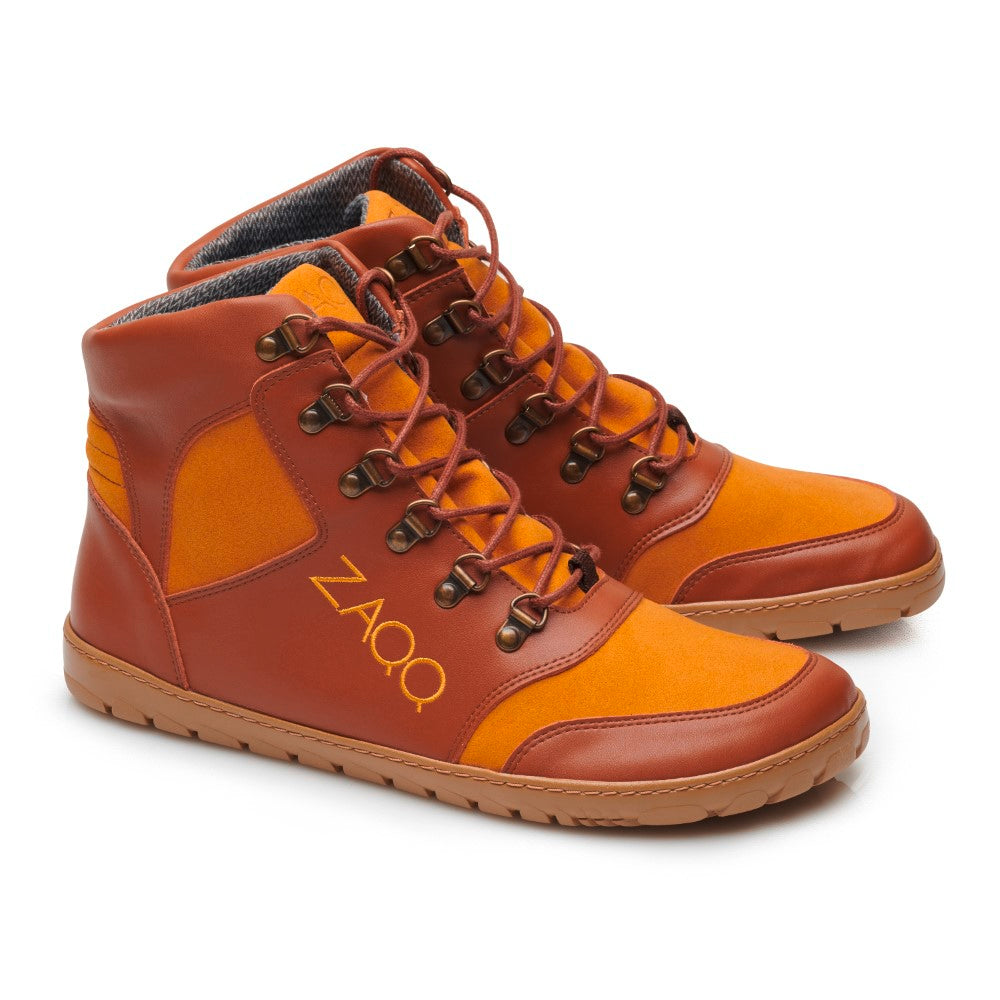 Ein Paar orange-braune High-Top-Schuhe namens HIQE Vegan Sierra Waterproof, auf deren Seite die Marke ZAQQ steht. Diese Barfußschuhe haben orangefarbene Schnürsenkel, eine braune Sohle und sind aus einer Mischung aus Leder und Stoff für ultimativen Komfort gefertigt.