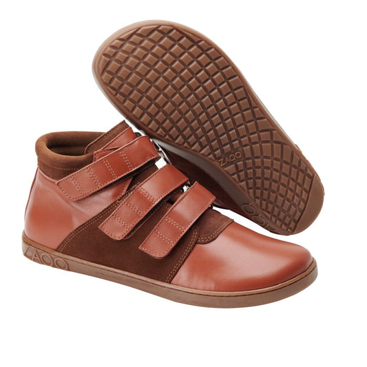 Der QOOPER Cognac von ZAQQ ist ein Paar hochwertiger brauner Leder-Sneaker mit Klettverschluss und passender Gummisohle. Diese aus hochwertigem Nappaleder gefertigten Sneaker zeigen ein zweifarbiges Design mit helleren und dunkleren braunen Abschnitten. Die Sohlen weisen ein Waffelprofil auf, wie von der Seite und von unten zu sehen ist.