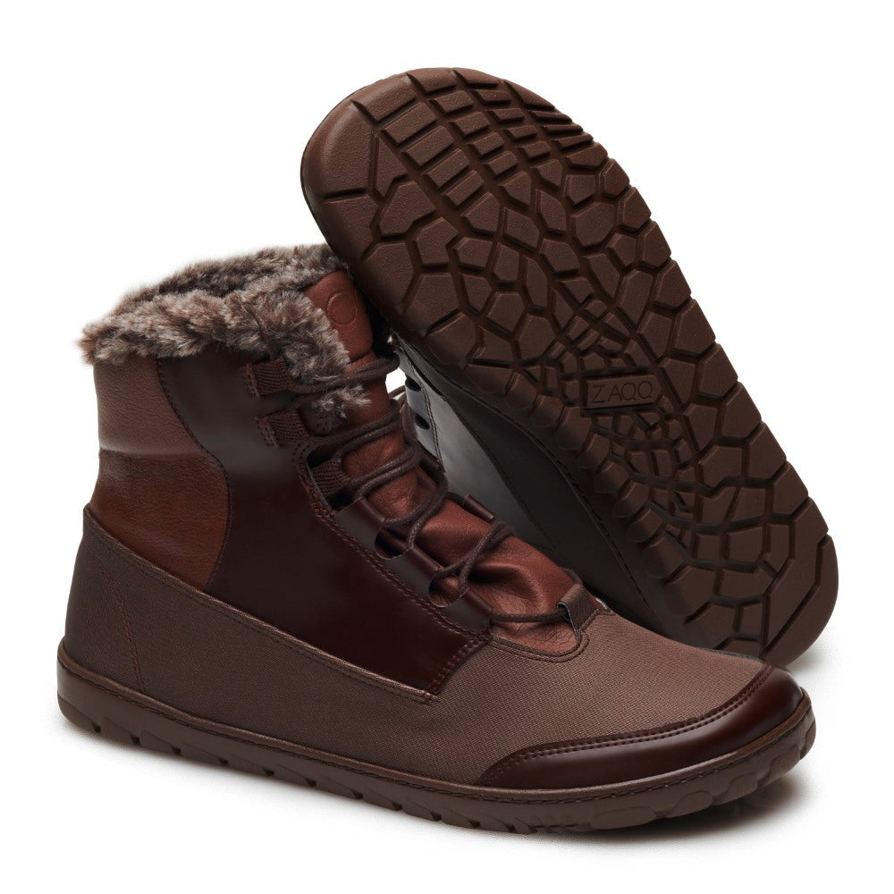 Wir präsentieren den QUEST Marone von ZAQQ: Ein Paar braune, hochgeschlossene Winterstiefel für draußen mit kuscheligem Kunstfellfutter. Diese stylischen Wanderstiefel haben eine strukturierte Sohle und ein Schnürdesign. Ein Stiefel steht aufrecht und zeigt seinen robusten Charme, während der andere flach liegt und die raffinierten Details der Sohle hervorhebt.