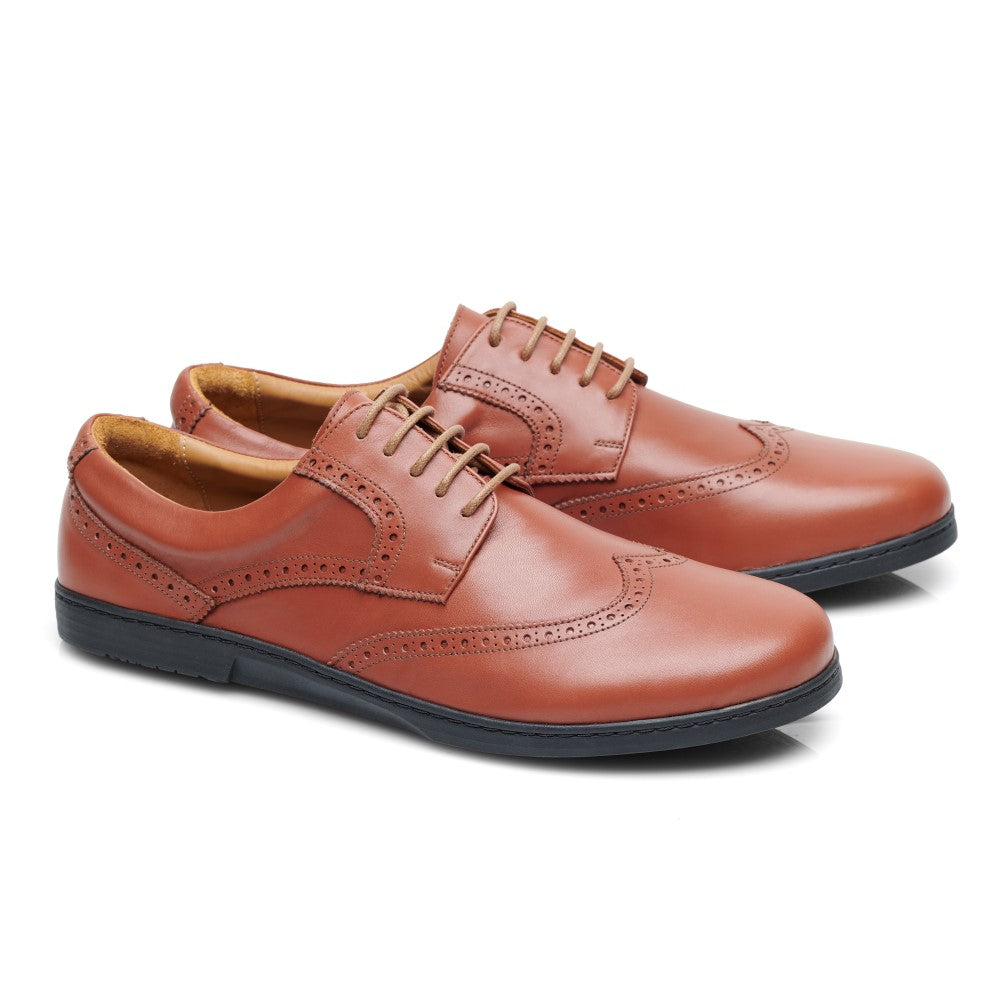 Wir präsentieren den BRIQ Brogue Cognac von ZAQQ, ein Paar luxuriöser Business-Schuhe aus braunem Leder mit schwarzen Sohlen. Diese Schuhe weisen aufwendige Nähte und dekorative Perforationen an den Rändern auf, die aus einem leichten Winkel elegant hervorgehoben werden, um ihre Handwerkskunst und exquisiten Designdetails hervorzuheben.