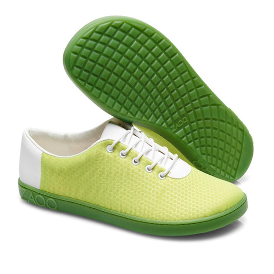 Ein Paar stylische vegane QARO Light Green Sneaker von ZAQQ mit grüner Sohle und gelbgrünem Mesh-Obermaterial mit weißen Akzenten. Der Markenname ZAQQ ist deutlich auf der Sohle und an der Seite zu sehen. Ein Schuh steht aufrecht, während der andere das Waffelmuster hervorhebt und so die Bewegungsfreiheit Ihrer Füße betont.