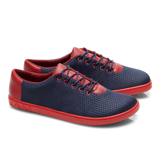 Wir präsentieren den QARO Navy Red von ZAQQ: ein Paar stylische Barfuß-Sneaker mit blauem Wabenmuster, ergänzt durch rote Zehenkappen, Schnürsenkel, Absätze und strapazierfähige Kautschuksohlen. Das Design ist sportlich und modern zugleich.