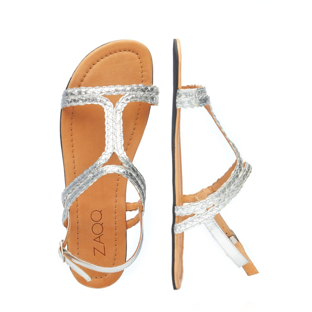 Drauf- und Seitenansicht eines Paars QOSTA Silver Sandalen von ZAQQ, ideal für Sommermode. Diese geflochtenen Ledersandalen haben eine flache Sohle mit hellbrauner Innensohle und ein T-Riemen-Design, das den eleganten QOSTA-Stil verkörpert. Der Markenname ZAQQ ist auf der Innensohle sichtbar und unterstreicht den Komfort dieser Barfuß-Sandalen.