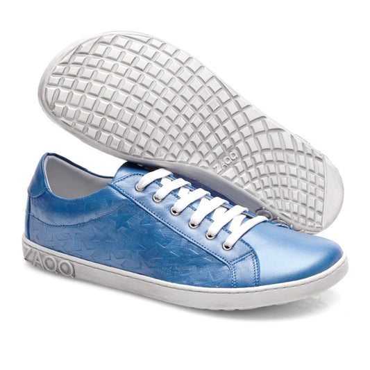 Der SLOQ Stars Blue von ZAQQ ist ein Paar glänzender blauer Sneaker mit Sternenmuster und weißer Sohle. Ein Sneaker steht aufrecht, während der andere auf der Seite liegt, wodurch das aufwendige Profilmuster der Sohlen hervorgehoben wird. Diese Schuhe sind aus glattem Nappaleder gefertigt und mit weißen Schnürsenkeln ausgestattet und vereinen nahtlos Stil und Komfort.