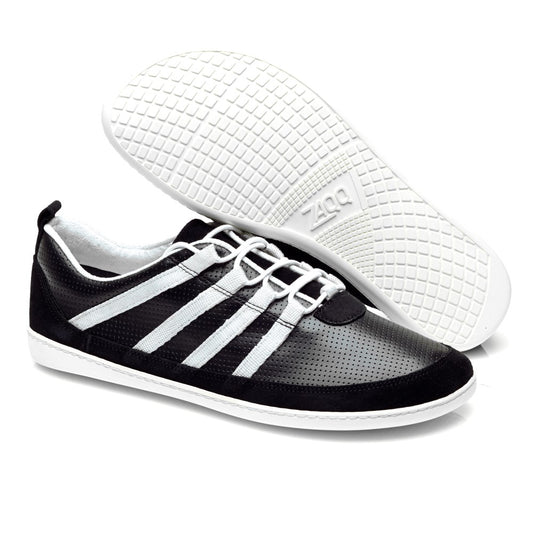 Die SPARQ Low Black White Sneaker von ZAQQ bestechen durch ihr schwarzes, sportliches Design mit weißer Sohle und Schnürsenkeln. Diese Schuhe zeichnen sich durch markante weiße Streifen an den Seiten aus und verfügen über ein perforiertes Obermaterial für optimale Belüftung. In der Präsentation steht ein Sneaker aufrecht, während der andere mit der Sohle nach oben positioniert ist, wodurch sein Griffmuster hervorgehoben wird.